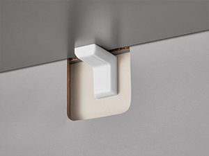 Vista ravvicinata di un apparecchio di illuminazione minimalista a parete in bianco su sfondo grigio, che mostra un design geometrico pulito.